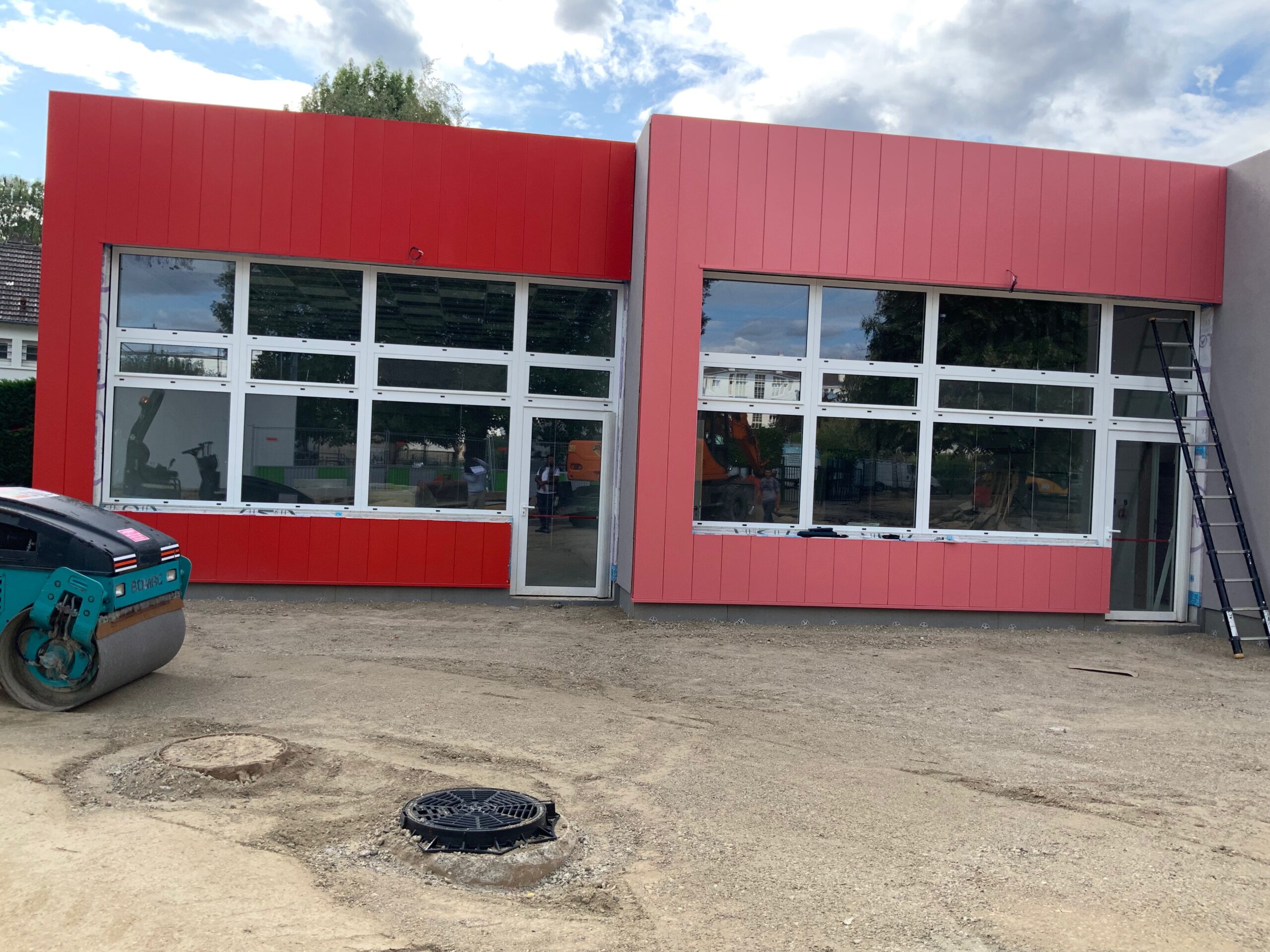 Ouvrier en désamiantage portant une combinaison de protection et un masque respiratoire, retirant un panneau en amiante dans une zone confinée.