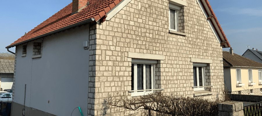 Maison individuelle avant travaux d'isolation thermique par l’extérieur (ITE), avec façade en pierres apparentes et pignon partiellement crépi.