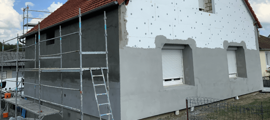 Pose de panneaux isolants et enduit sur la façade d’un pavillon dans le cadre d’une isolation thermique par l’extérieur (ITE).