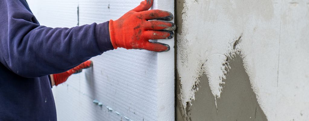 Pose d’un panneau isolant en polystyrène sur une façade extérieure dans le cadre d’une isolation thermique par l’extérieur (ITE)
