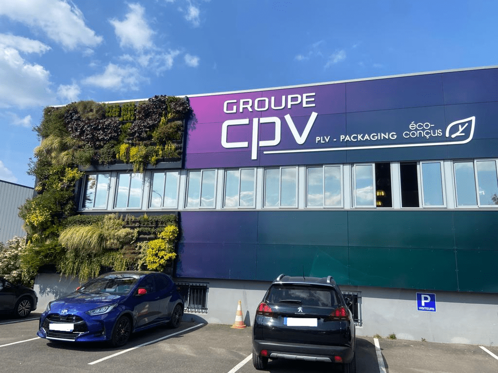 Façade rénovée du siège CPV Plus avec logo, bardage végétalisé et panneaux colorés