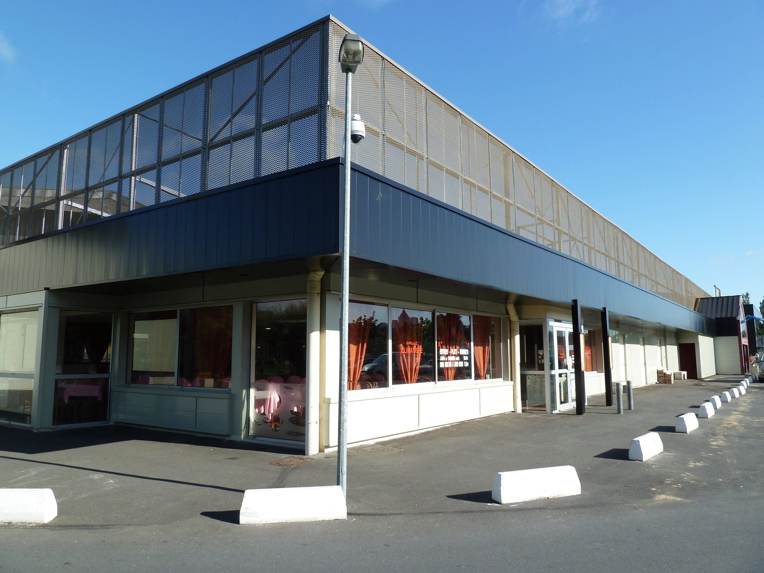 Façade rénovée d’un centre commercial avec bardage métallique et parement décoratif ajouré