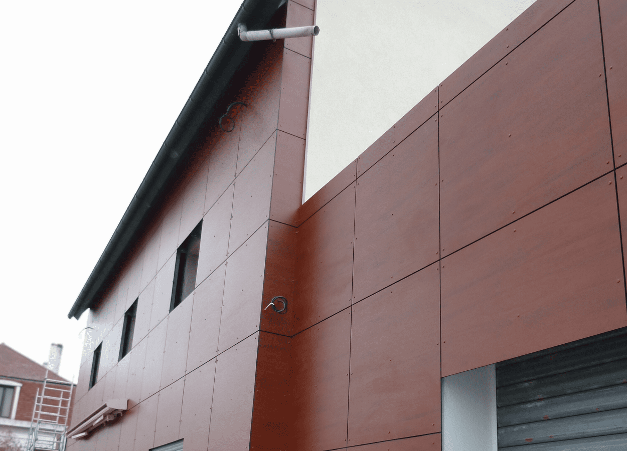 Pose d’un isolant en laine minérale et bardage métallique dans le cadre d’une isolation thermique par l’extérieur (ITE) sur bâtiment tertiaire.